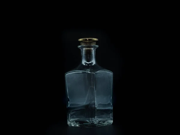 空のガラスボトルは黒の背景に隔離された大きな黄金の丸いコルクで閉じます 透明な四角いボトル 垂直滞在瓶の正面図 — ストック写真
