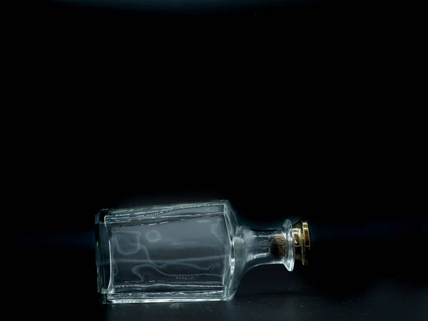 黒の背景に一本の空のガラス瓶 透明な四角いボトル 横の透明な四角形の瓶の上の敷設の正面図 — ストック写真