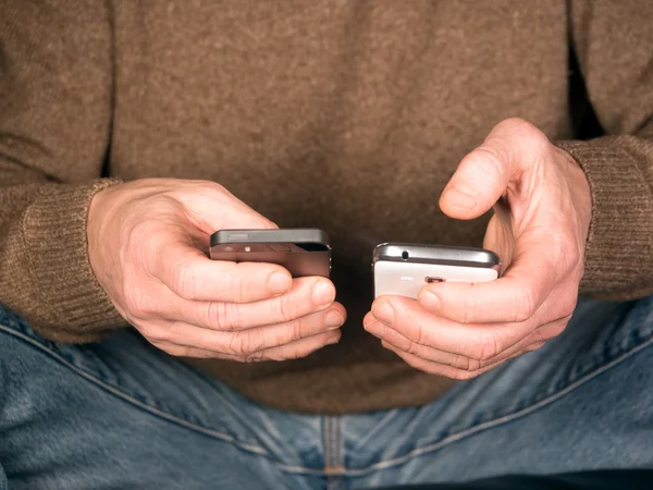 Händer som håller två smartphones — Stockfoto