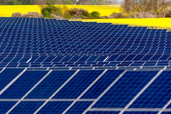 Painéis solares em um campo de colza — Fotografia de Stock