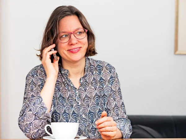 Vrouw met smartphone en kopje koffie — Stockfoto