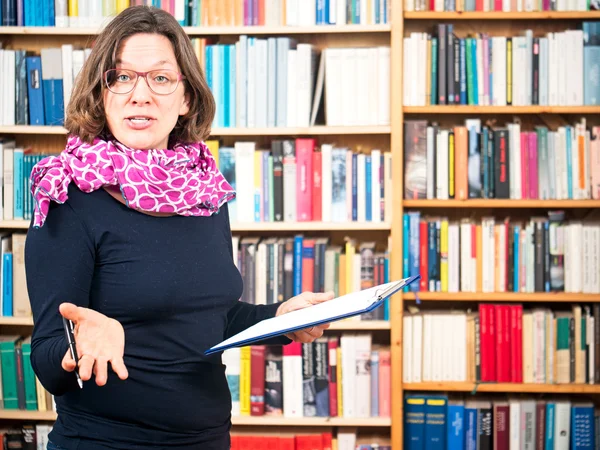 Vrouw leest voor boekenkasten — Stockfoto