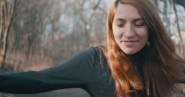 Siyah kaplumbağa boyunlu neşeli kızıl saçlı adam sabah ormanında dans ediyor..