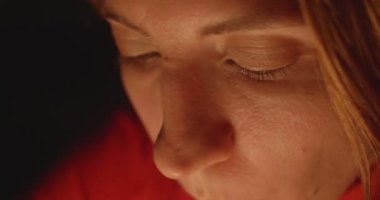 Kırmızı bluz giyen kadın karanlık bir odada mumları üflüyor..