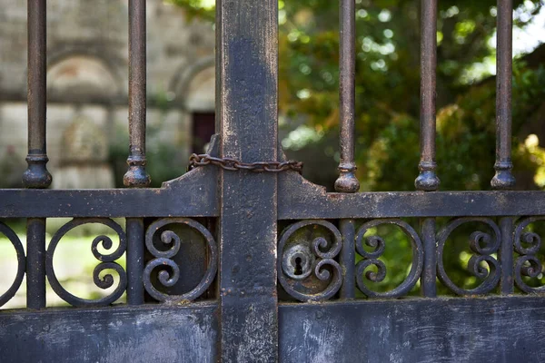 Weathered wrought iron gate in front of an old property