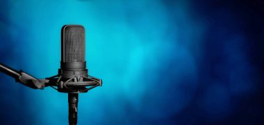 Mavi arka planda stüdyo mikrofonu kaydediliyor. Müzik üretimi, radyo ya da podcast afişi