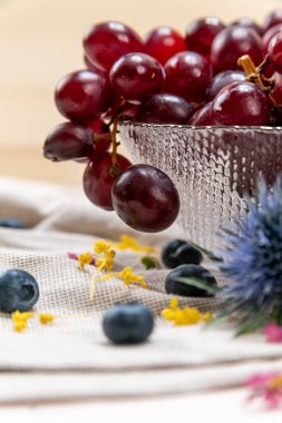 Kristal bir kasede yaban mersini ve yabani çiçeklerle kırmızı üzümlerin ayrıntıları.