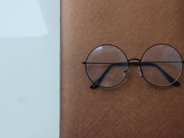 Beyaz masanın üzerinde bir not defteri olan bir gözlük.