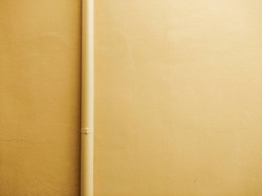 Beton duvar ve altın renkli düz bir boru.