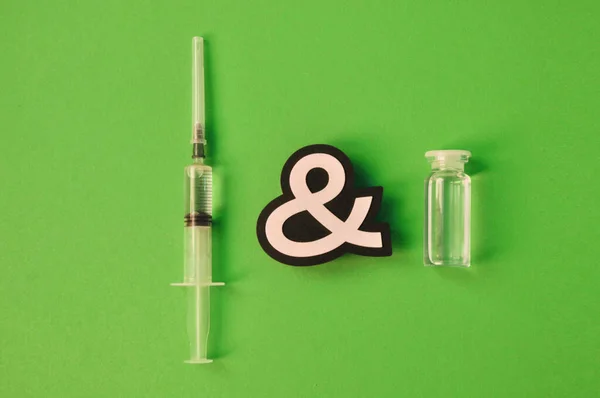 Transparent bottle with virus vaccine with injection syringe on green background, vaccine sputnik for the treatment of the coronavirus. Copyspace for text