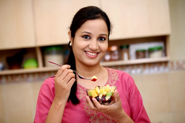 Gülümseyen genç Hintli kadın yeme meyve salatası
