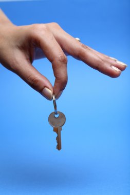 Mavi arka plan üzerinde bir anahtar tutan el