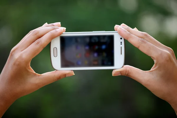Inteligentny telefon trzymając się za ręce kobiety — Zdjęcie stockowe