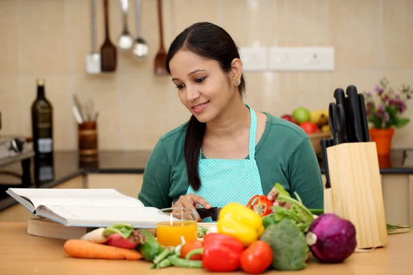 Young woman reading a cook book in her kitchen