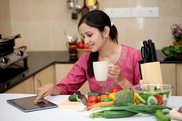 Young Indian woman drinking coffee in her kitchen Stock Photo