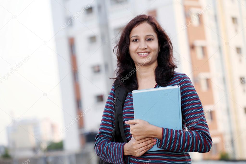 Smiling young female student holding books