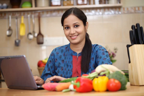 Young Indian woman using a tablet computer in her kitchen Stock Image