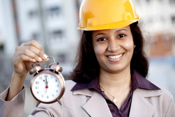 Жінка інженер-будівельник тримає будильник — стокове фото