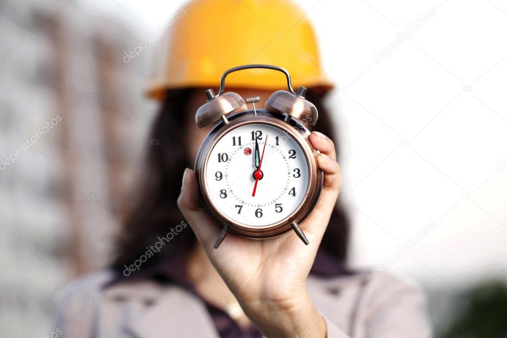 Female construction engineer with alarm clock
