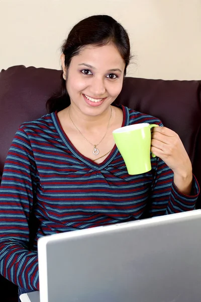 Glückliche Frau trinkt Kaffee, während sie am Laptop arbeitet — Stockfoto