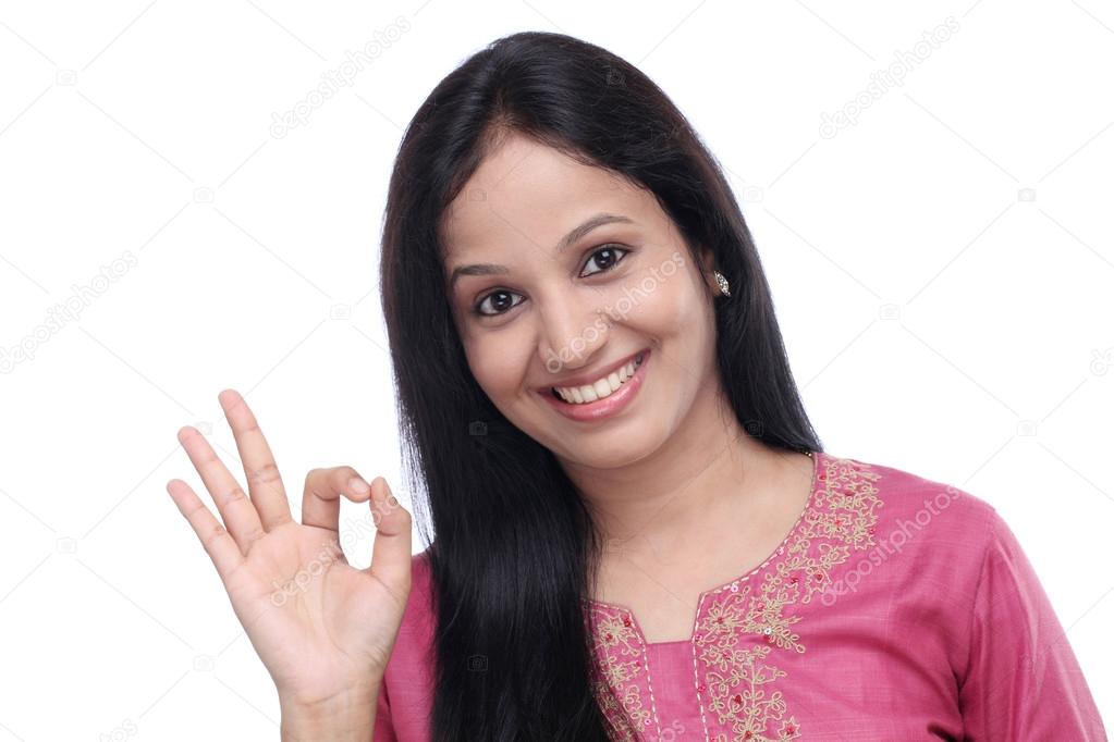 Young Indian woman showing OK sign against white 