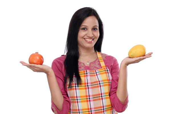 Jovem mulher vestindo avental de cozinha e segurando frutas — Fotografia de Stock