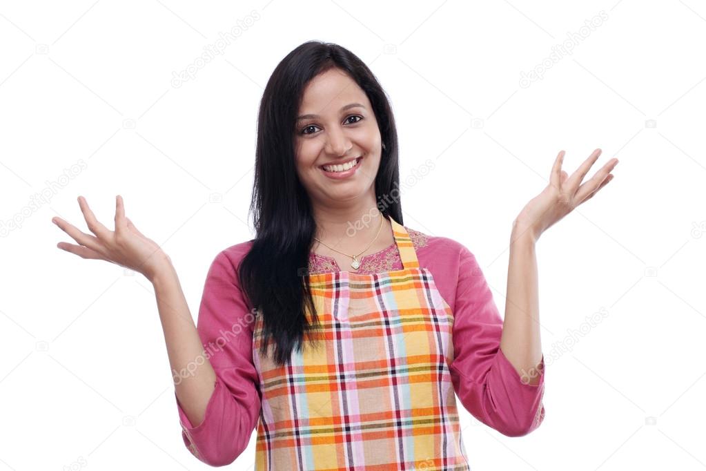 Excited young woman wearing kitchen apron against white 