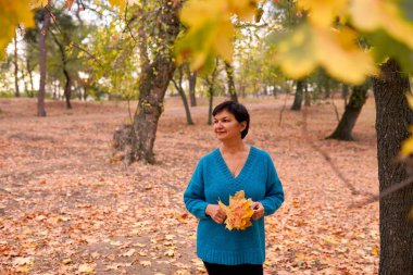 Güzel beyaz kadın sonbahar zamanı dışarıda yürüyüp eğleniyor. Parlak yeallow renkleri
