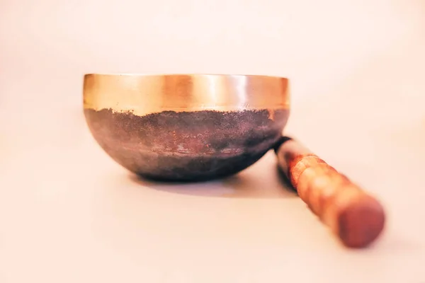 Bronze tibetan singing bowl with wooden stick on the white background. Sound healing, sound bath therapy