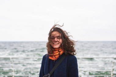 Deniz kenarındaki kışlık ceketli mutlu kadın.