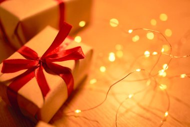 Kırmızı kurdeleli ve bulanık ışıklı Noel hediyesi kutusu