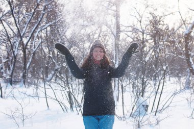 Güzel bir kadın karlı ormanda eğleniyor. Kış açık hava aktivitesi