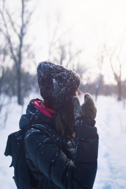 Güzel bir kadın karlı ormanda eğleniyor. Kış açık hava aktivitesi