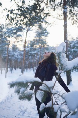 Güzel bir kadın, karlı ormanda kışa eşlik ediyor. Kış açık hava aktivitesi