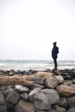 Güzel bir kadın kışın martılarla kumsalda yürüyor..