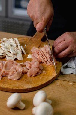 Şef yanında mantar olan tahta bir helikopterde tavuk göğsü dilimliyor..