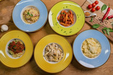 Ahşap arka planda farklı soslu makarna ve spagetti tabakları, üst manzara. İtalyan yemeği kavramları.