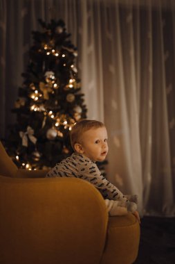 Mutlu Noeller ve mutlu tatiller! Çocuk tuhaf bir şekilde tatil dekorundaki ışıklara bakıyor.