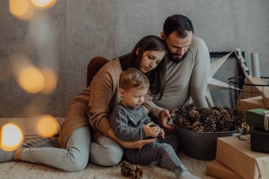 Genç bir çocukla genç bir aile, evdeki tatil dekorunda samimi anlar geçirir..