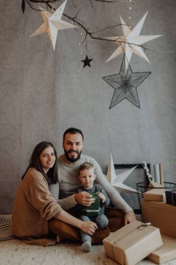 Genç, güzel bir anne ve baba Noel dekoru stüdyosunda eğleniyorlar..