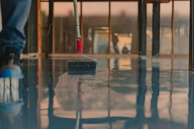 İşçi yeni kata gri epoksi reçine sürüyor.