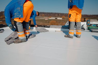 Worker prepares geotextile for the roof, covers it with synthetic PVC membrane clipart