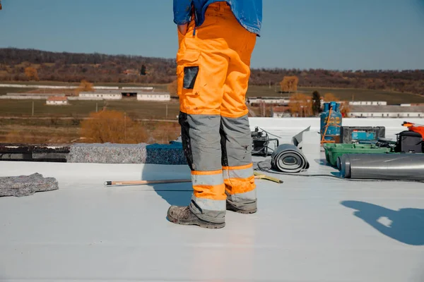 Çatı tamircisi, pvc membranlı yalıtım sistemi olan düz bir çatıda çalışıyor.