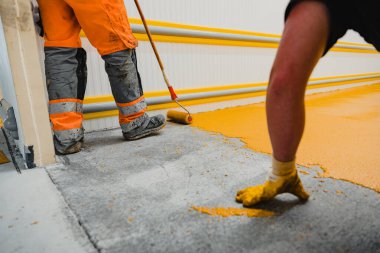 Worker applying epoxy and polyurethane flooring system.These easy-to-clean products also have non-slip features. clipart