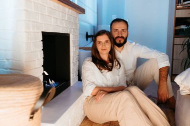 Çift modern bir şöminenin başında dinleniyor, birlikte rahat vakit geçiriyorlar.