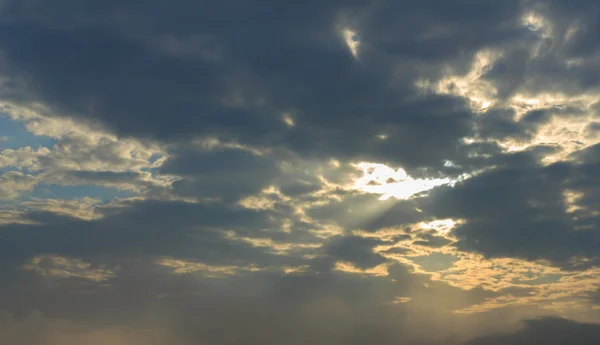 Rays of sun light shining through dark clouds on dark sky for background — Stock Photo, Image