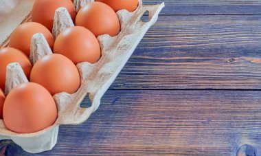 Tahta bir arka planda karton bir kutuda çiğ tavuk yumurtası. Yukarıdan manzara. Yemek arkaplanı, kopyalama alanı. Sağlıklı beslenme kavramı.