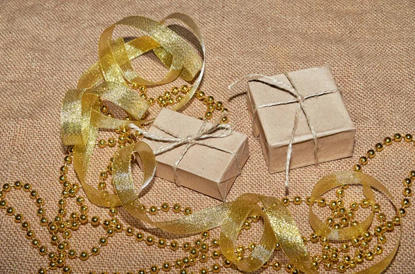 Різдвяні коробки в ремісничому папері лежать на столі, прикрашені золотими стрічками і бісером. Різдвяний фон. Святковий фон. Вид зверху . — стокове фото