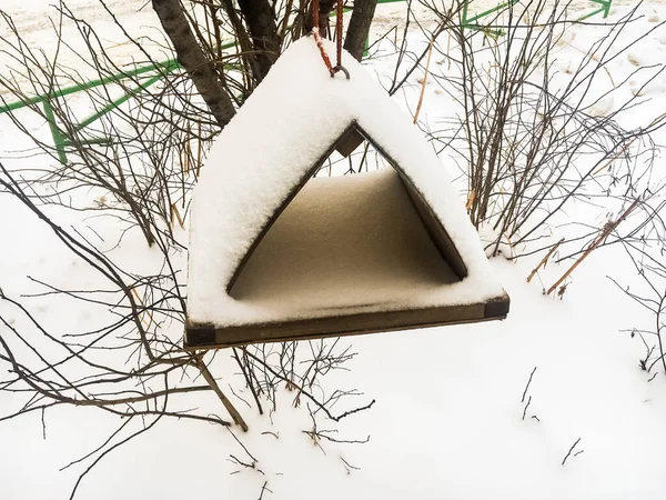 Paisagem de inverno, alimentador de pássaros, coberto de neve contra a neve e ramos de arbustos. Close-up. — Fotografia de Stock