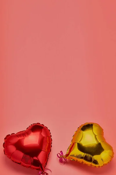 Vzduchové balónky ve tvaru srdce, červené a zlaté, na růžovém pozadí. Koncept lásky, Valentýna, oslavy, svátky. Kovový balón. Ležel. Místo ke kopírování. — Stock fotografie